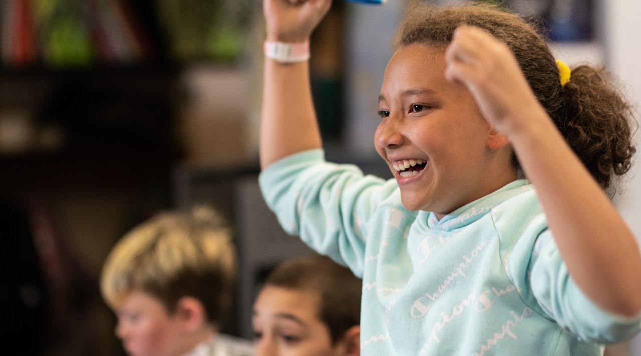 An Academy District 20 student raises her arms in celebration.